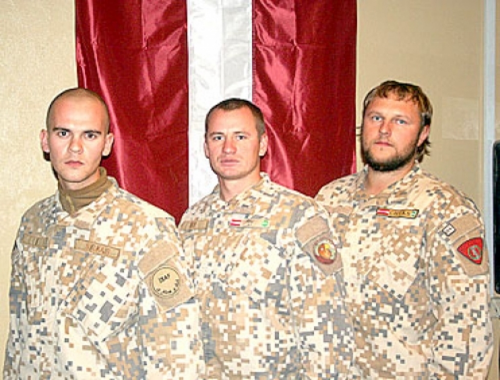 18. novembrī pie Latvijas valsts karoga Afganistānā trīs karavīri no Bauskas rajona Īslīces pagasta: ložmetējnieks, dižkareivis Sergejs Kukajs (no kreisās), nodaļas komandieris, seržants Jānis Abuhovs un nesprāgušās munīcijas neitralizēšanas nodaļas galvenais operators, virsseržants Andris Palamarčuks. 
Autors: No albuma.