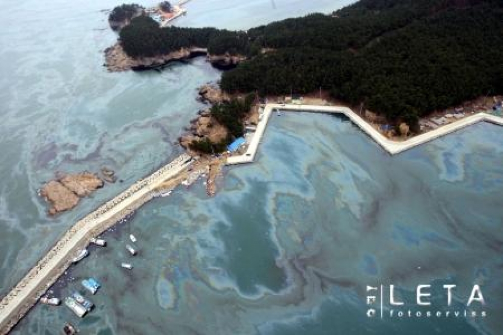 No lidmašīnas uzņemtā fotoatēlā redzams naftas piesārņojums Dienvidkorejas Dzeltenās jūras piekrastē. No avarējušā tankkuģa 