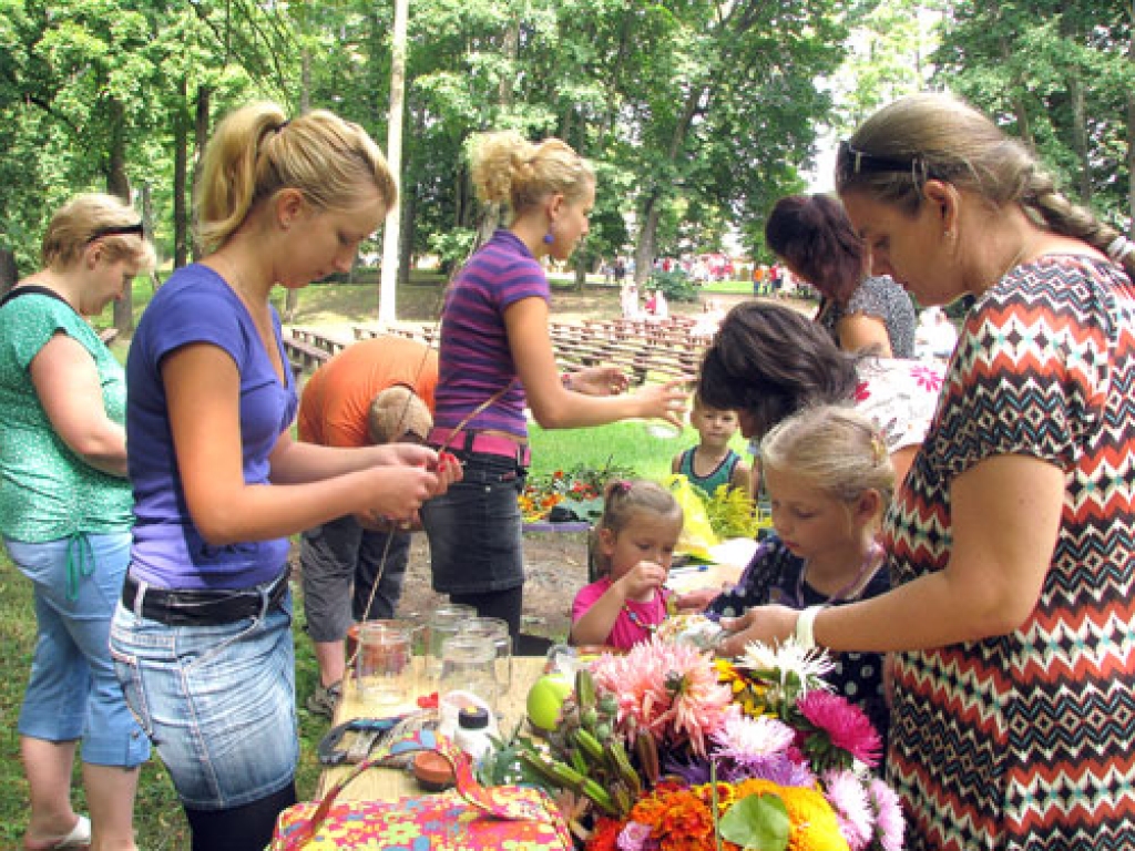 Radošās floristikas darbnīcas bērniem vadīja Zane Cera (no kreisās) un Terēze Kaufelde. Svetlana Jevstigņejeva (no labās) ar meitiņu Marinu gatavo lukturīti. Viņas uz Ziedu svētkiem bija atbraukušas no Rīgas. Ar mammu un meitu kopā bija tētis un  ciemos atbraukušie radi no Krievijas. Svetlana par pasākumu izlasījusi avīzē «Subbota» (no krievu val. – «Sestdiena»).  Foto centrā mazā meitenīte – trīsarpus gadu vecā iecavniece Elīza. Viņai palīdz mamma Ineta Bramane. Par dalību radošajās darbnīcās nebija jāmaksā. 
Autors: Juris Iļņickis