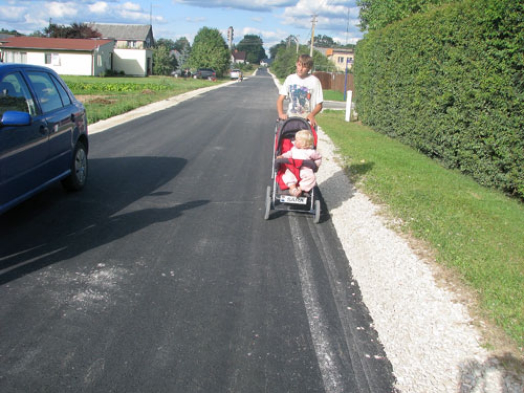 «Putekļi vairs nebūs jāelpo aiz braucošām automašīnām. Vieglāk iet, netraucē akmeņi. Turklāt smuki izskatās,» par asfaltēto Rūpniecības ielu teic iecavnieks Edijs Lagzdiņš. Viņš ratiņos stumj māsīcu Sāru Lagzdiņu. 
Autors: Juris Iļņickis