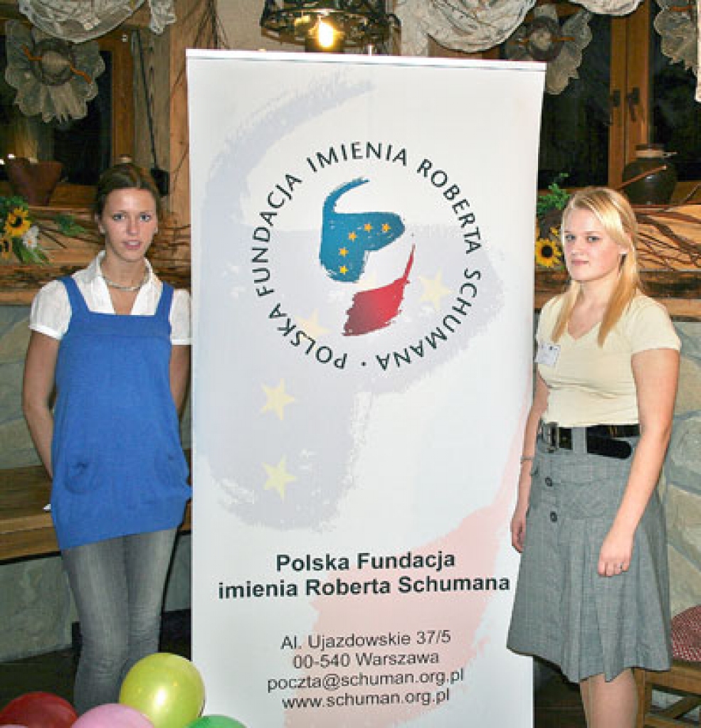 Ilze Pole (no kreisās) un Anda Krēgere pie konferences plakāta.