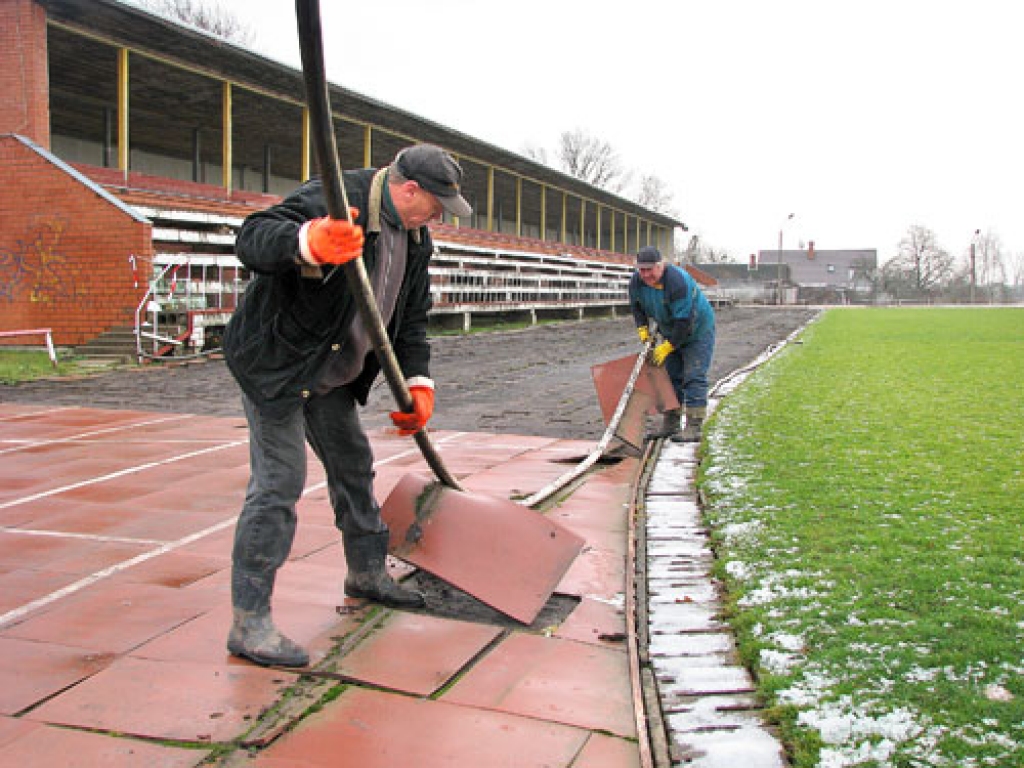 Mežotnieki Valērijs Vasiļjevs (priekšplānā) un Edmunds Mašinskis novāc seguma plāksnes no Bauskas rajona pašvaldības sporta bāzes skrejceļa.