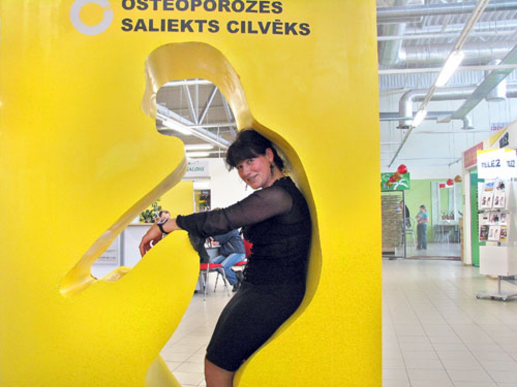 Ceraukstiete Anita Bužeriņa mēģināja ielocīties maketā, lai pārliecinātos, kā osteoporoze izliec mugurkaulu.