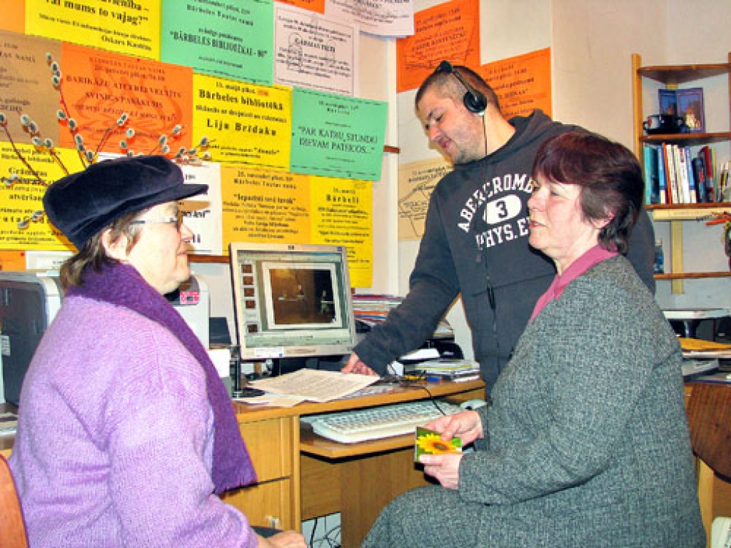 Bārbeliešus Līviju Simu (no kreisās) un Renāru Goževicu ar Bārbeles pagasta literātu apvienības sarīkojumu fotohroniku iepazīstina bibliotēkas vadītāja Brigita Krauze.