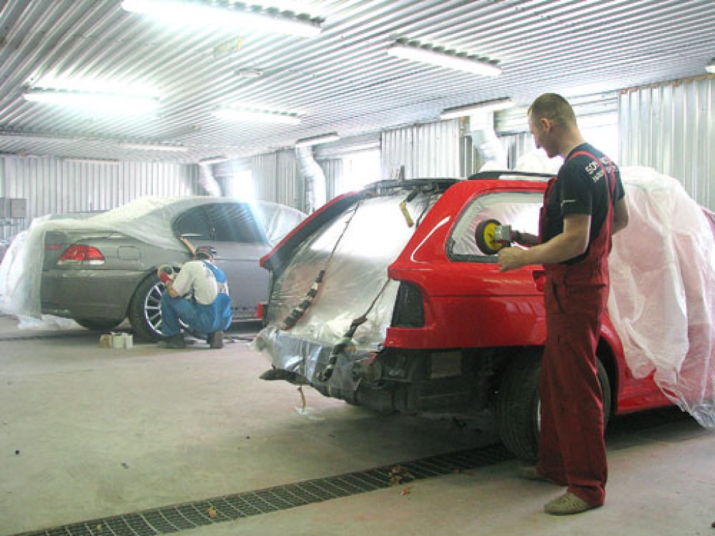 SIA «Teiksmas» autoservisa krāsošanas sagatavošanas telpā ar automašīnām strādā krāsotājs Juris Kursišs (priekšplānā) un virsbūves remonta ceha vadītājs Ivo Tenis.