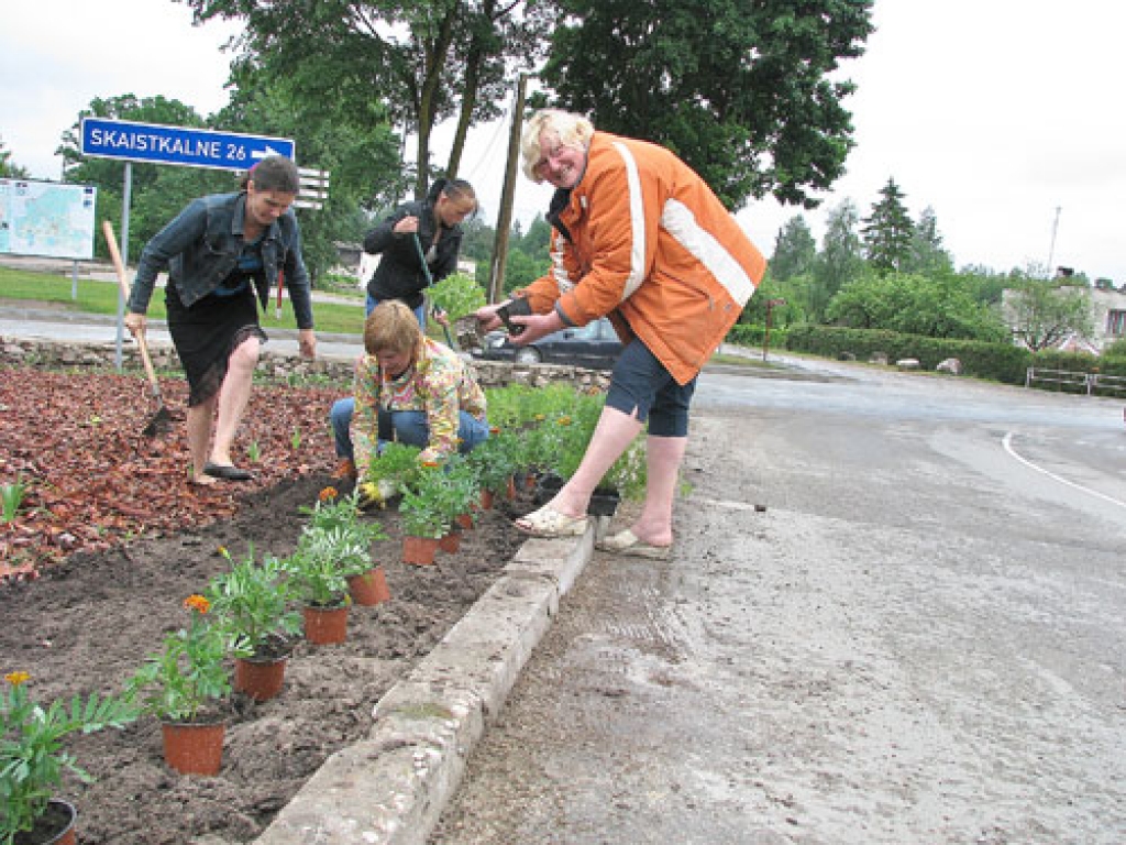 Leontīna Grinberga (no labās) stāsta: «Ilgi gaidījām lietu, lai dobes malas apstādītu ar samtenēm, kas jau zied.» Puķes stādīja Līga Veismane, Jautrīte Haritonova un Ieva Grigane. 