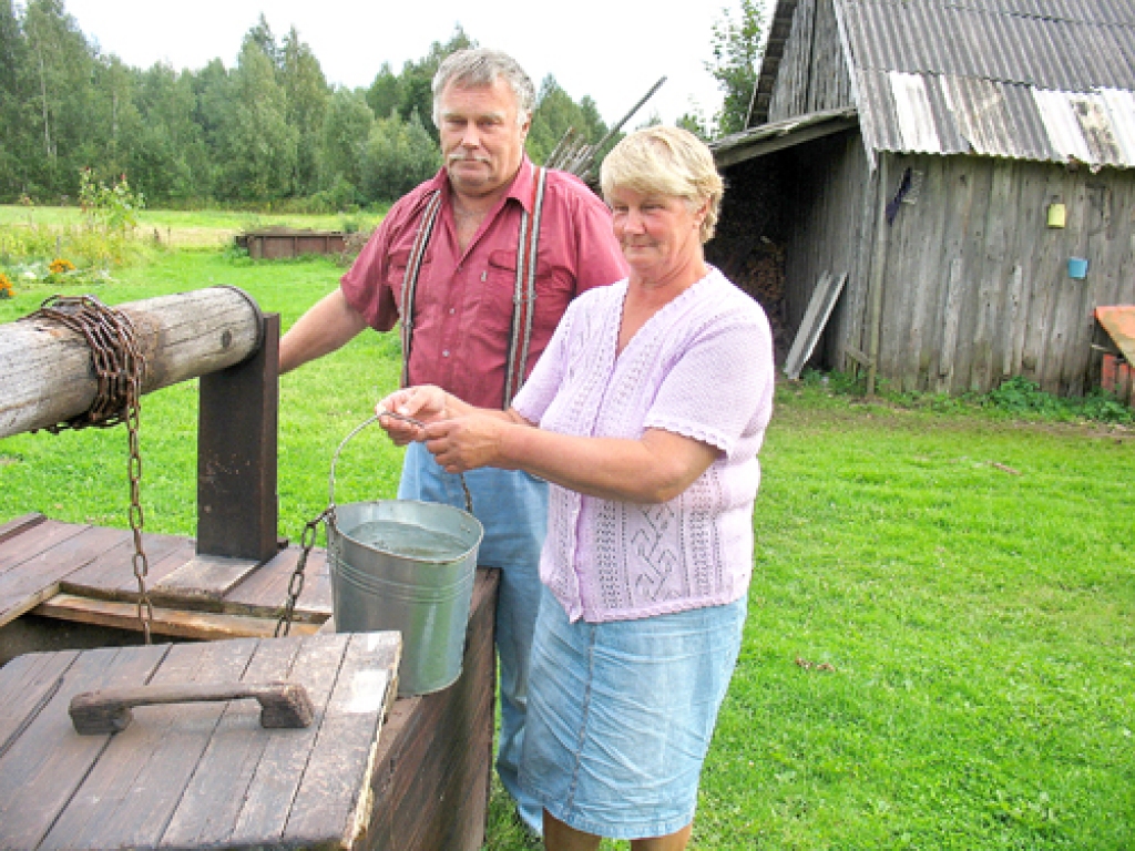 Dvīņi Vilnis Vārpa un Vija Raupa smeļ ūdeni no savu senču akas. Vilnis vecāku mājās «Ataugas» piedzimis un nodzīvojis visu mūžu.
