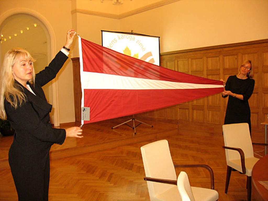 Ārlietu ministrijas darbinieces Sintija Stipre (no kreisās) un Zane Ampermane demonstrē jauno Latvijas karoga vimpeli. 
Autors: Vilnis Auzāns