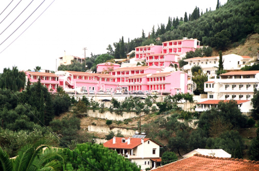 Hostelis «The Pink Palace» (‘Sārtā pils’ – angl.) attaisnoja savu nosaukumu. Pirmajā vakarā sārtajās ēkās spietoja jaunieši, kuru galvenais apģērba gabals bija iesārts palags, otrajā dienā pludmalē pietauvojās sārts izpriecu kuģītis. Ar olīvkokiem un cipresēm apaugusī nogāze, kuru izdaiļoja citrusaugļu mazdārziņi, veidoja fonu sārtajām ēkām. No istabiņas balkona varēja skatīt klinšu ieskauto pludmali.