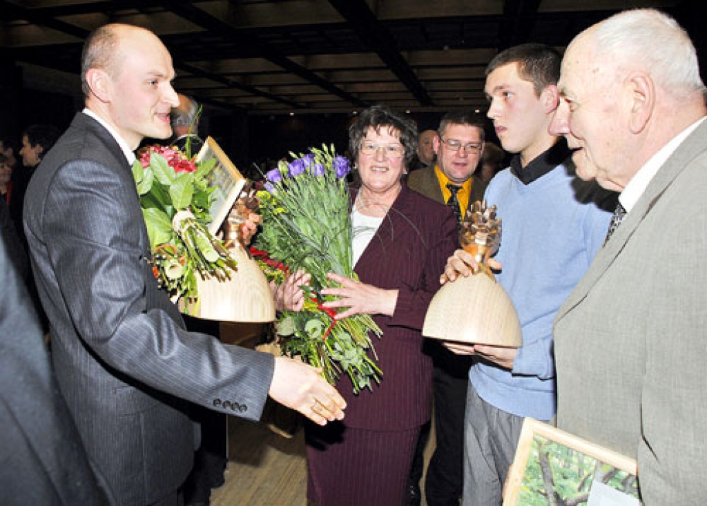 Bārbelietis Jānis Folkmanis (no kreisās) apsveic meža nozares veterānu Egīlu Āboliņu (no labās), ar kuru kopā bija kuplā ģimene, arī mazdēls Egīls, Latvijas Lauksaimniecības universitātes trešā kursa students, topošais mežsaimnieks. Apsveikumus un ziedus saņēma arī laureāta sieva Ruta Āboliņa. 
Autors: Ivars Bogdanovs