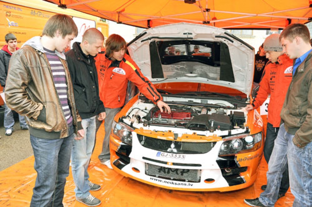 Topošie automehāniķi Māris Bajārs (no labās), Nauris Bušmanis (no kreisās) un Emīls Kārkliņš ieklausās autosportistu brāļu Anda un Māra Neikšāna stāstījumā, kurā viņi raksturo sporta mašīnas īpatnības. 
Autors: Ivars Bogdanovs