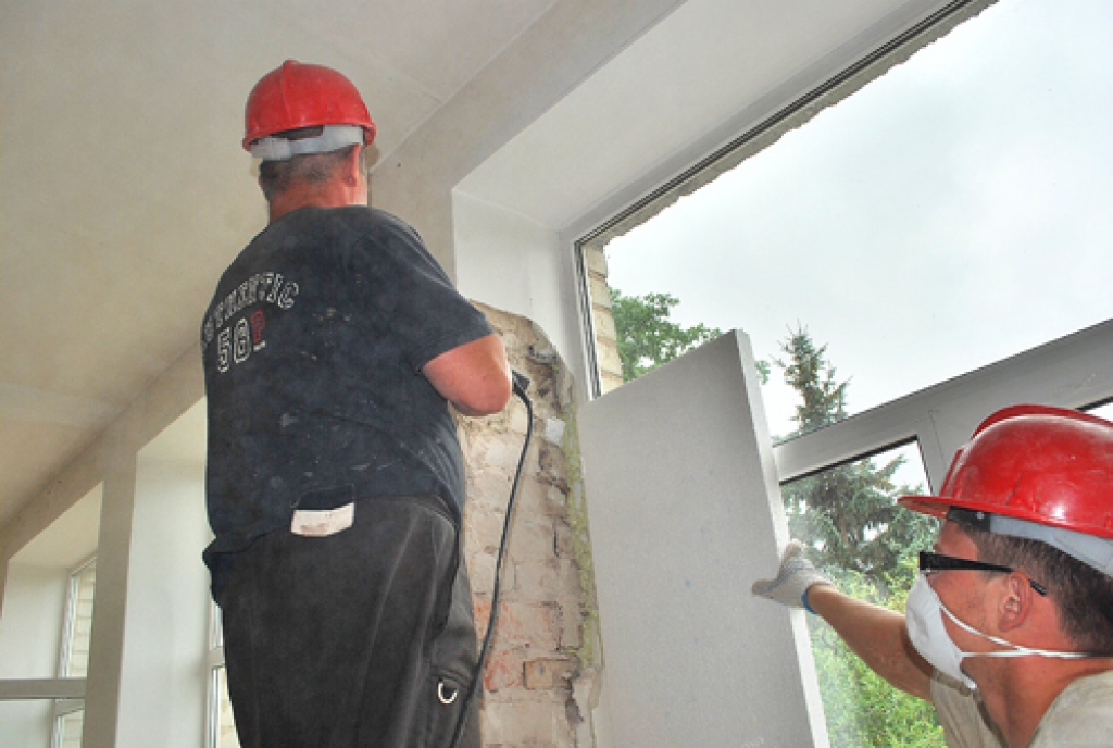 SIA «Modus būve» darbinieki bērnudārzā «Pasaulīte» nokaļ logu ailēm apmetumu, lai varētu veidot papildu siltinājuma slāni. 