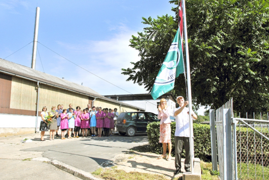 Aivars Svarenieks, SIA «Kronis» valdes loceklis, skanot aplausiem un klātesot biedrības «Mārketinga padome» vadītājai Ingūnai Gulbei, paceļ mastā «Kvalitātes karogu». 