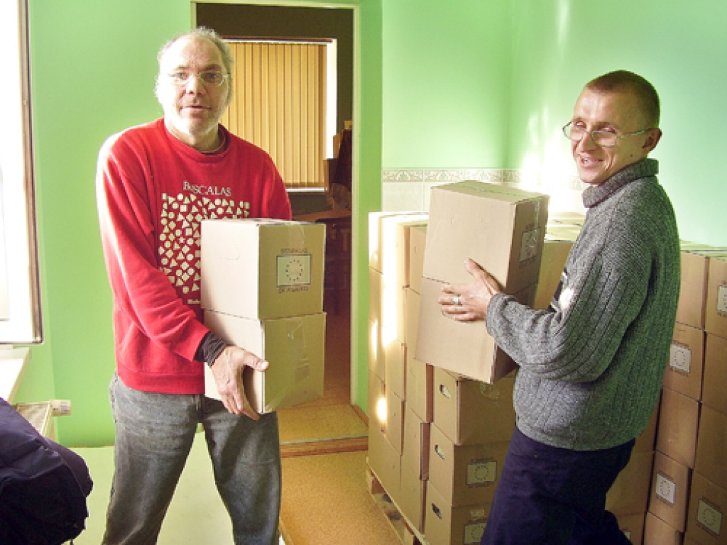 Māris Briņķis un Juris Ancāns, simtlatu stipendiju programmā nodarbinātie, Sarkanā Krusta komitejas noliktavā izkravāja pārtikas paku kravu.