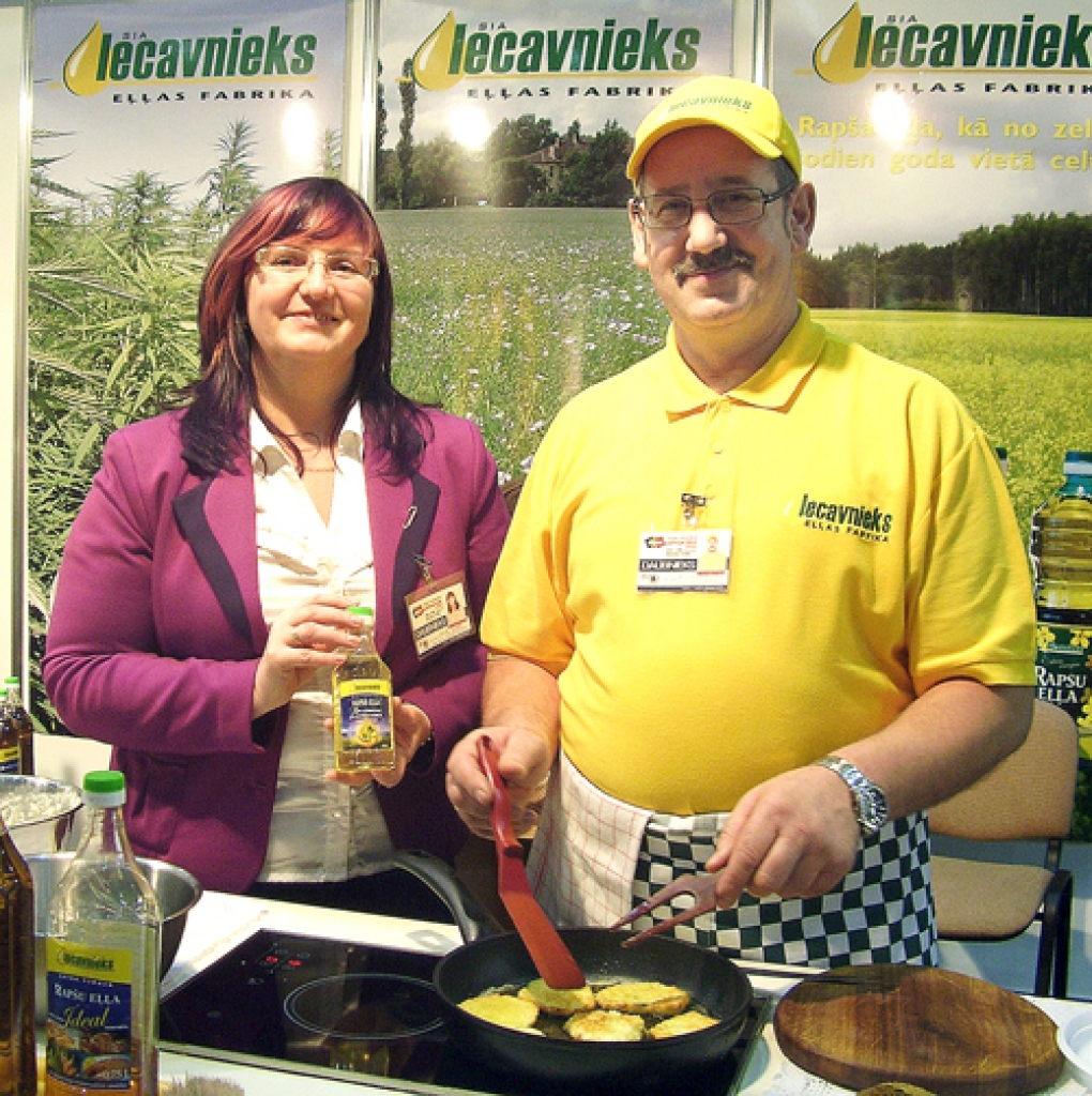 SIA «Iecavnieks» stendā tirdzniecības vadītāja Ineta Gulbe stāsta par jauno produkciju, bet pankūkas cep Ritvars Gulbis. 