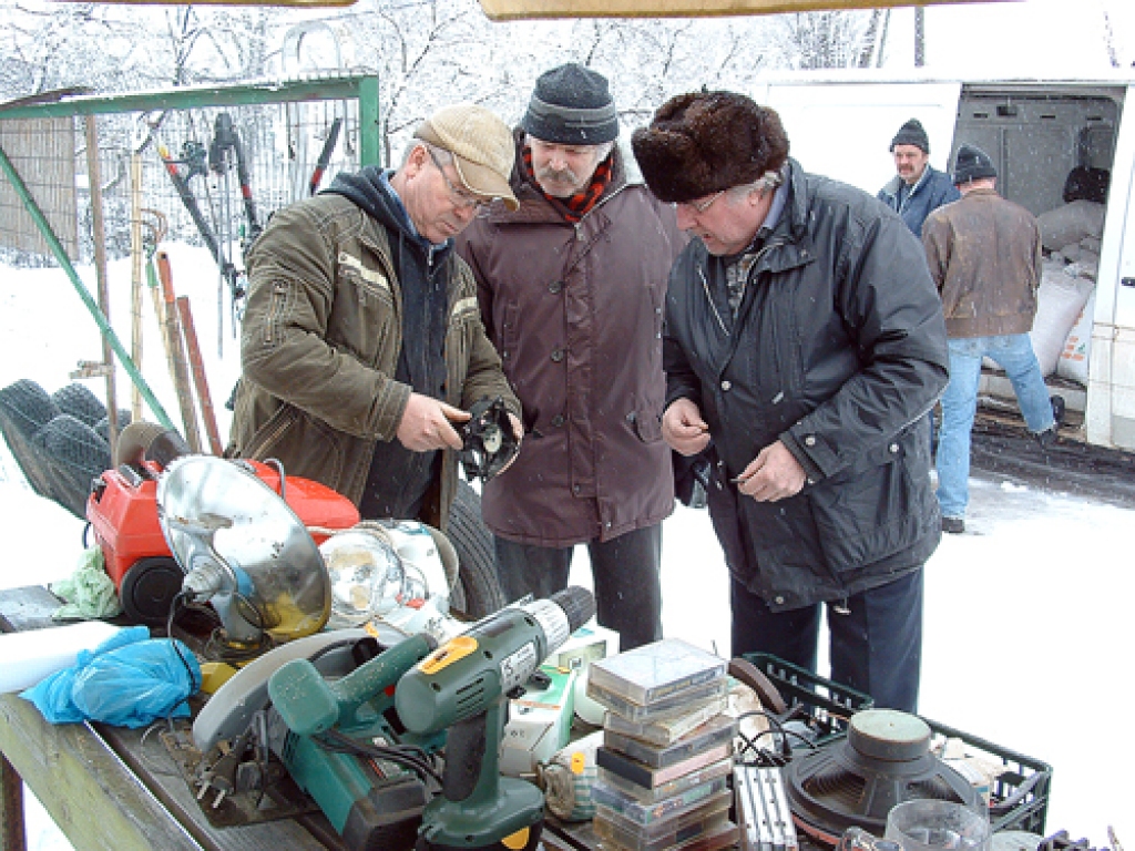Anatolijs Zikovs (no kreisās) cenšas pārdot elektrisko ventilatoru. 