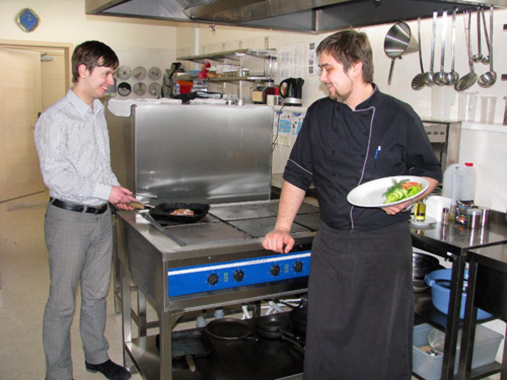 Ilgvars Putāns, viesnīcas «Bauska» direktors (no kreisās), ja nepieciešams, var stāties pie plīts, lai palīdzētu šefpavāram Maksimam Ugodņikovam pagatavot viesiem maltīti.