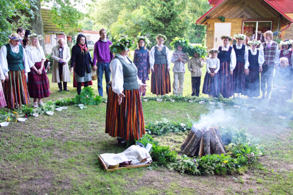 Dziedniece Laima Kārkliņa un jāņubērni ar vārdiem un dziesmām sagatavo ziedokli ugunij.