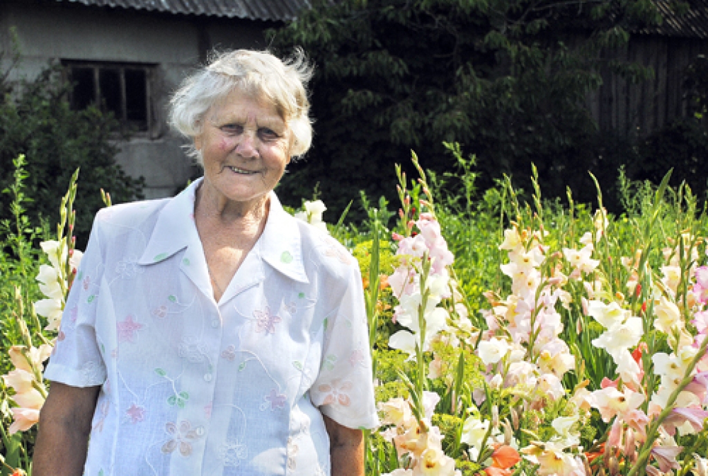 Jaunsauliete Marija Gulbe ar pašas izaudzētajām gladiolām rotā katoļu baznīcu.