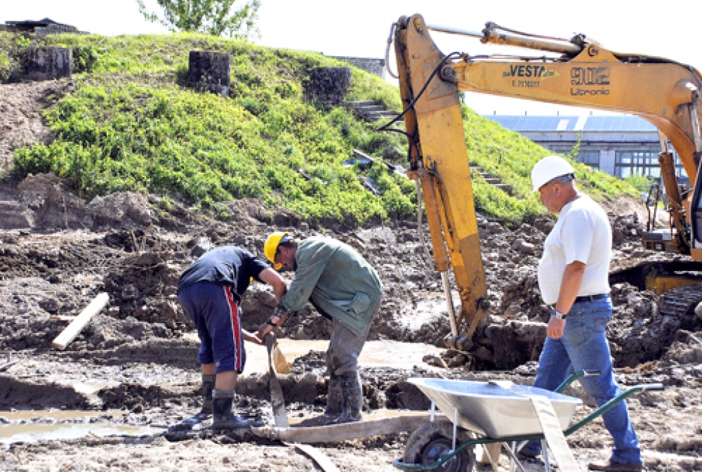 SIA «Vesta ABM» strādnieki gatavojas atsūknēt lietusūdeni, kas piepildījis topošās attīrīšanas stacijas būvlaukumu.