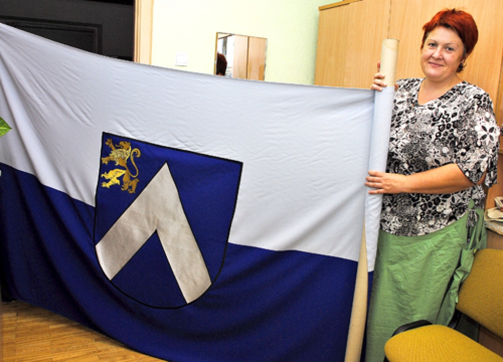 Andra Matuļenko rāda Bauskas novada karogu.