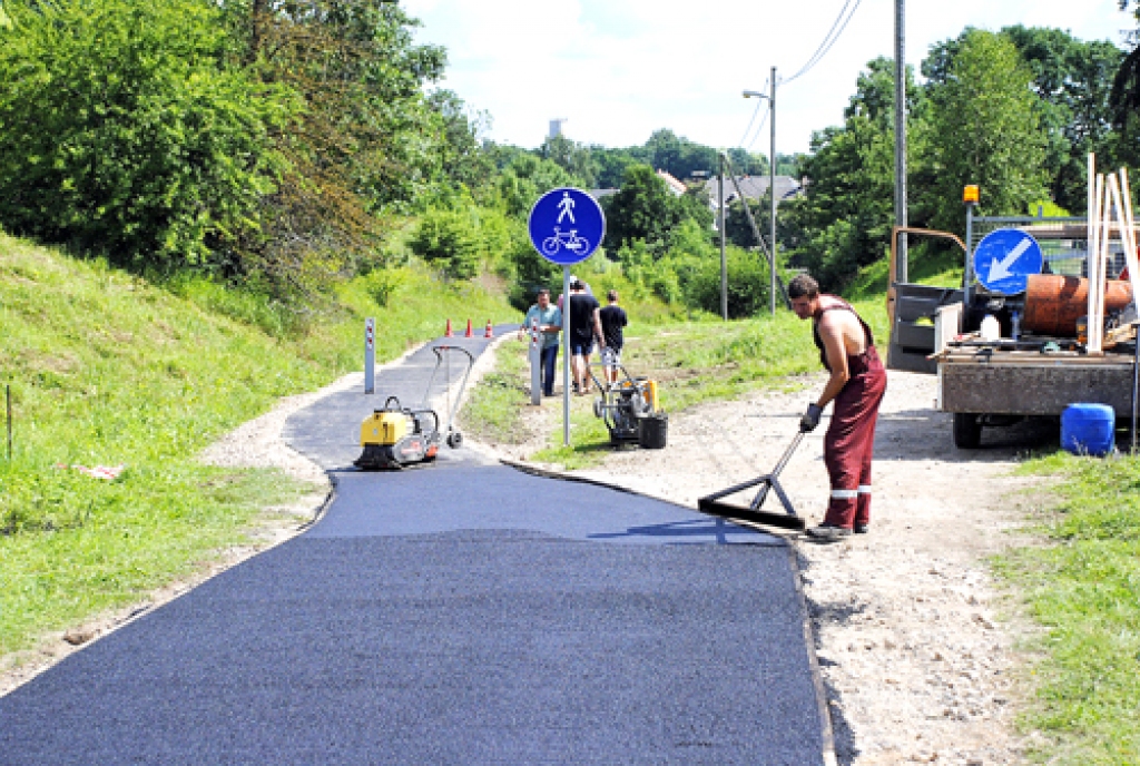Uzņēmuma «Vides serviss» darbinieki ieklāj asfalta segumu gājēju celiņā, kas no Kundziņkroga Codē ved lejup uz Bausku. 