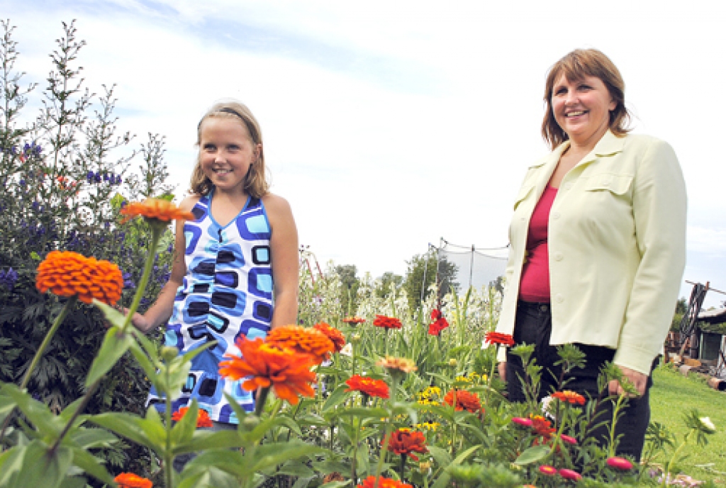 Vizma Štraumane piemājas puķu dobē ar jaunāko atvasi – meitu Elīzu Stellu. Abi dēli Gints un Agnis ir jau lieli un sākuši savu dzīvi. «Pie mazbērniem vēl neesmu tikusi. Tas vēl viens sapnis,» atklāj jubilāre. 
