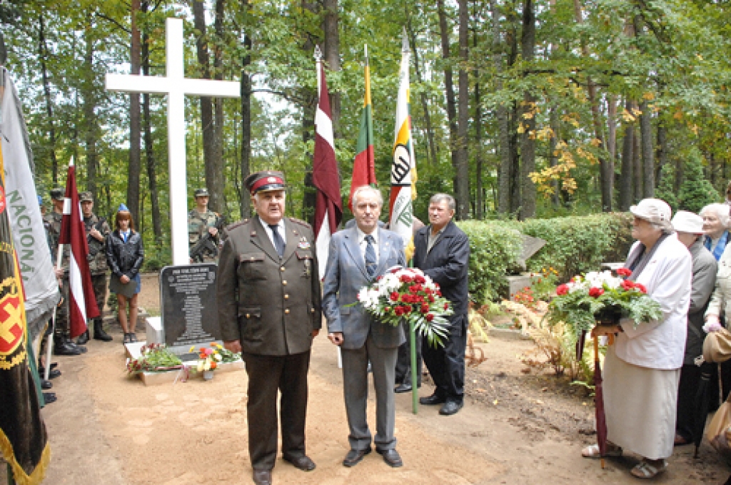 Piemiņas vietas atklāšana. Latvijas Nacionālo partizānu apvienības priekšsēdētājs Ojārs Stefans (priekšplānā no kreisās) svinīgā pasākuma apmeklētājus iepazīstina ar meistaru Hariju Frīdemani, kurš ieguldījis savu darbu un līdzekļus, izgatavojot Balto krustu.