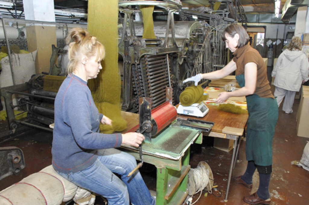 Vērpējas Olita Konstantinova (sēž no kreisās) un Irina Prusakova sver un fasē vilnas kārsumu.