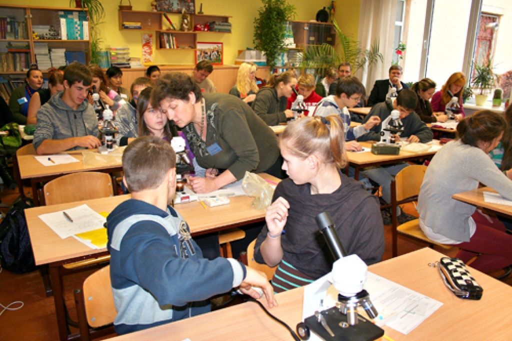 Ķīmijas stunda 8.a klasē, kuru vada skolotāja Ilze Cīrule. Semināra dalībnieki, kuru vidū ir arī Vecumnieku novada domes priekšsēdētājs Rihards Melgailis un Vecumnieku vidusskolas direktors Aivars Ķiņķevskis, vēro nodarbību. 