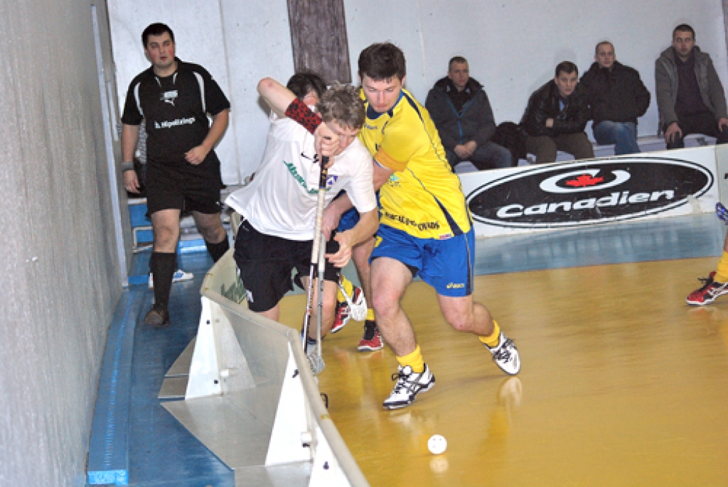 Pēteris Zeltiņš (baltajā tērpā no kreisās) pie borta cīnās par bumbiņu. 