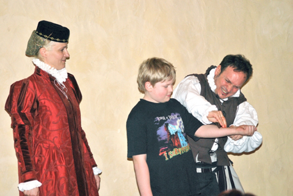 Kristoferam Voldemāram Gobiņam (vidū) roku «griež» Enriko Pecolli. Notiekošo uzmanīgi vēro Dace Pecolli. 