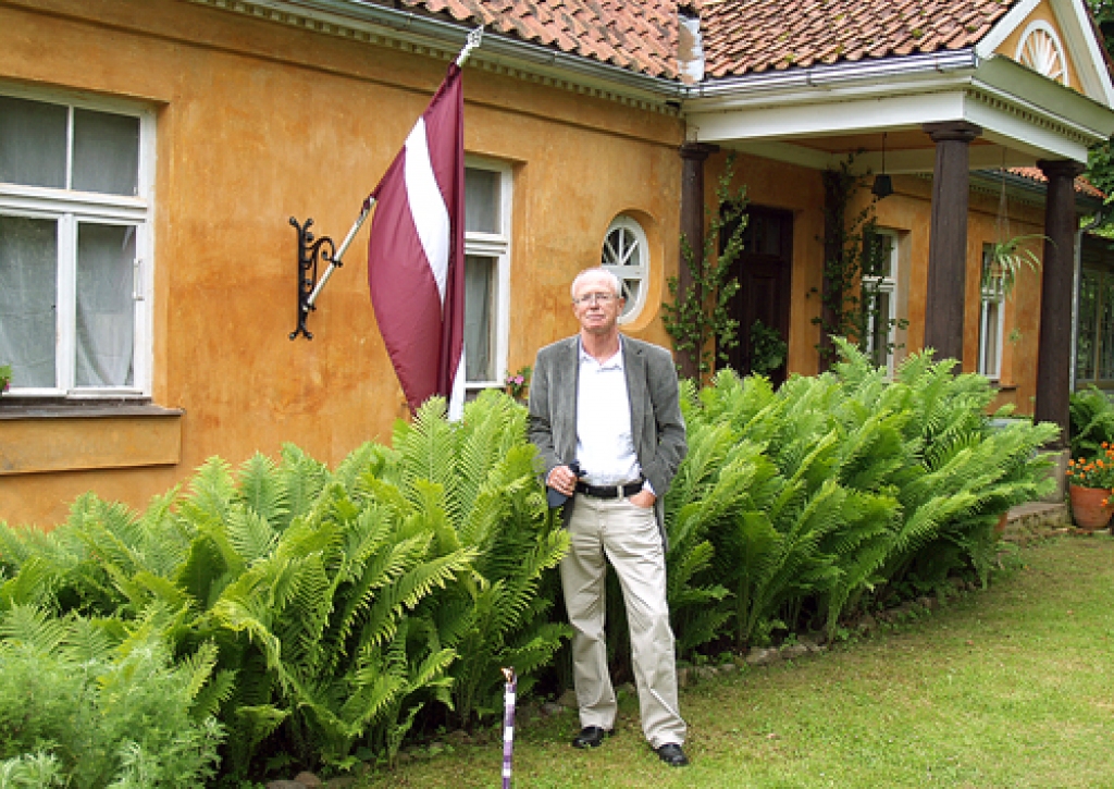 Maksims Strunskis, latviešu izcelsmes ārsts no Vācijas, pie paša dāvātā un uzvilktā Edvarta Virzas dzimtas māju karoga. 