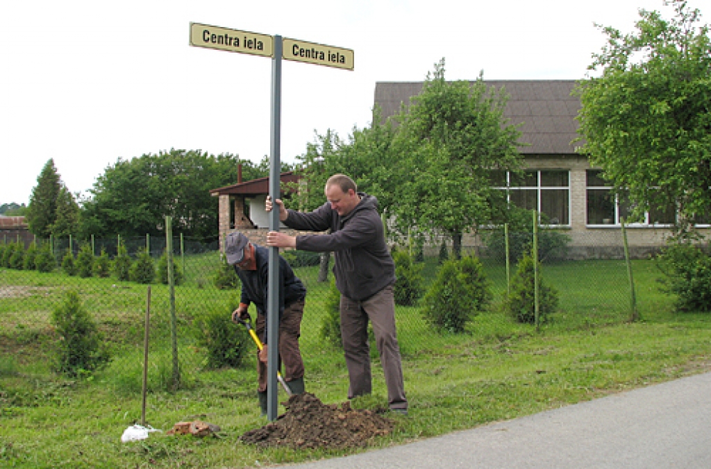 Strādniekam Aigaram Bruntālam (no kreisās) ielas nosaukuma plāksnīti palīdz uzstādīt Ivans Tjuhs. 
Autors: Vilnis Auzāns