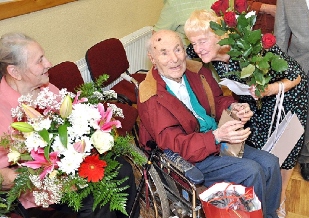 «Vai atceries mani?» jubilāram vaicā skolotāja Dzidra Kaminska (no labās). Viņai Jānis Pavilons bija labs kolēģis un draugs. No kreisās – jubilāra dzīvesbiedre Anna Spunīte. 