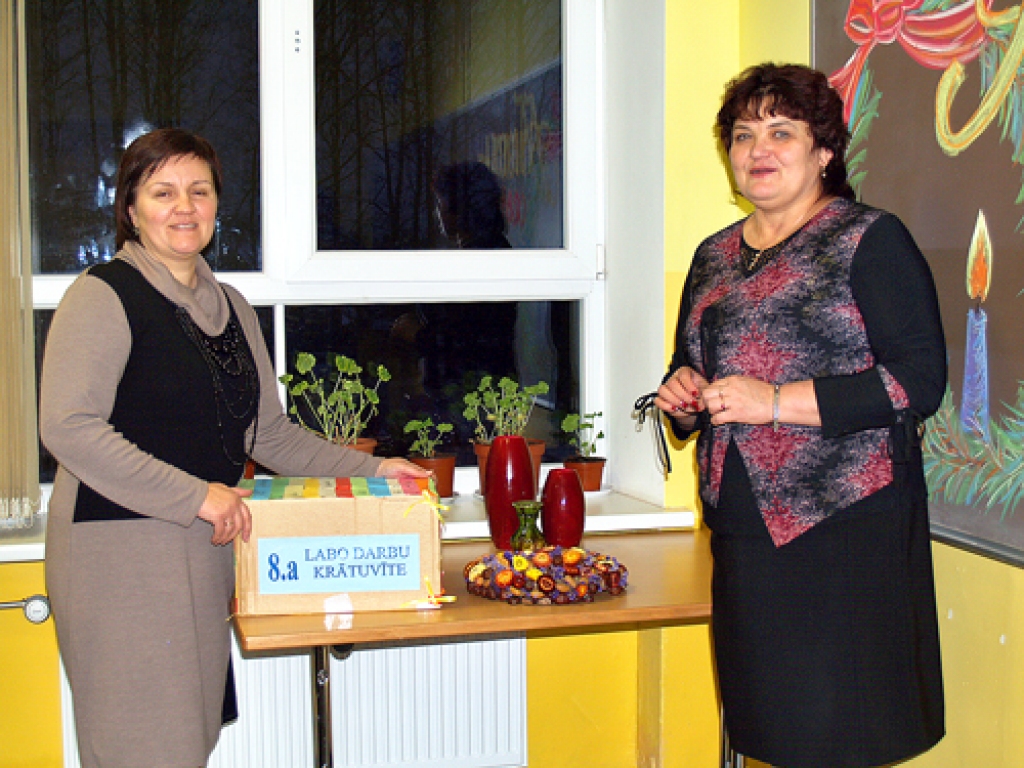 Aija Semjonova (no labās), direktore, un Natālija Novicka, 8.a klases audzinātāja, gandarītas par skolēnu centību ar labo darbu žetoniem piepildīt katrā klasē novietoto kasti. 