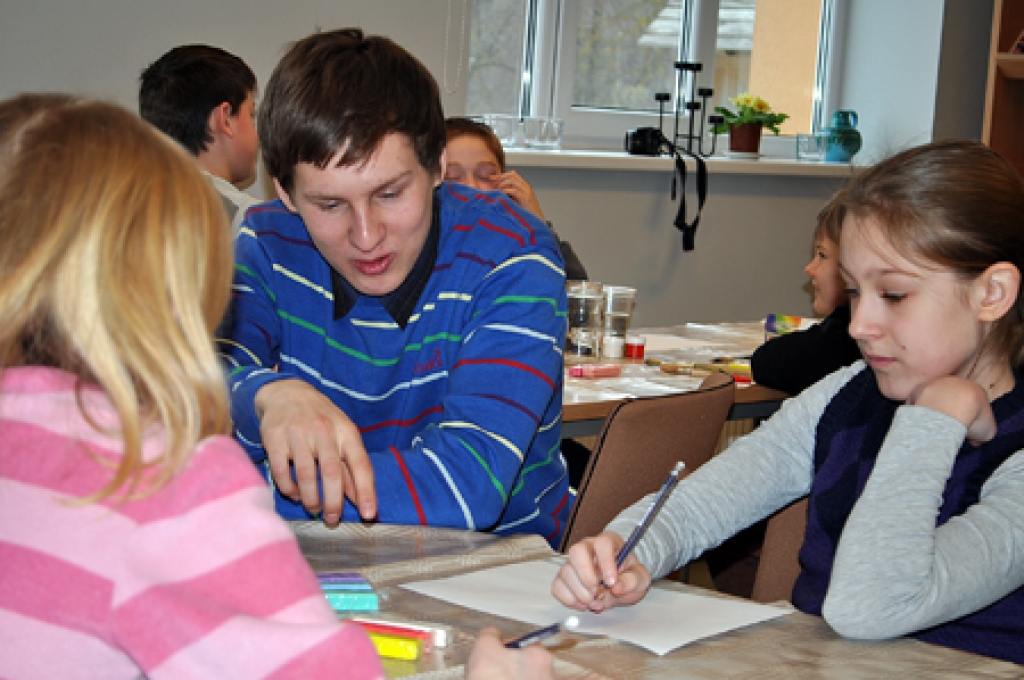 Reinis Pastars, darbnīcas vadītājs, skaidro animācijas filmiņas tapšanas procesu Enijai Šustai. 