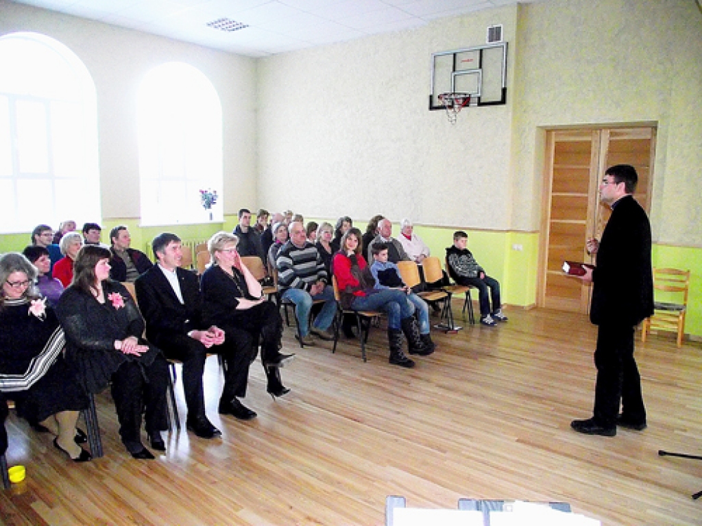 Mācītājs Edgars Mažis sarunā ar cilvēkiem Stelpes pamatskolas zālē.  