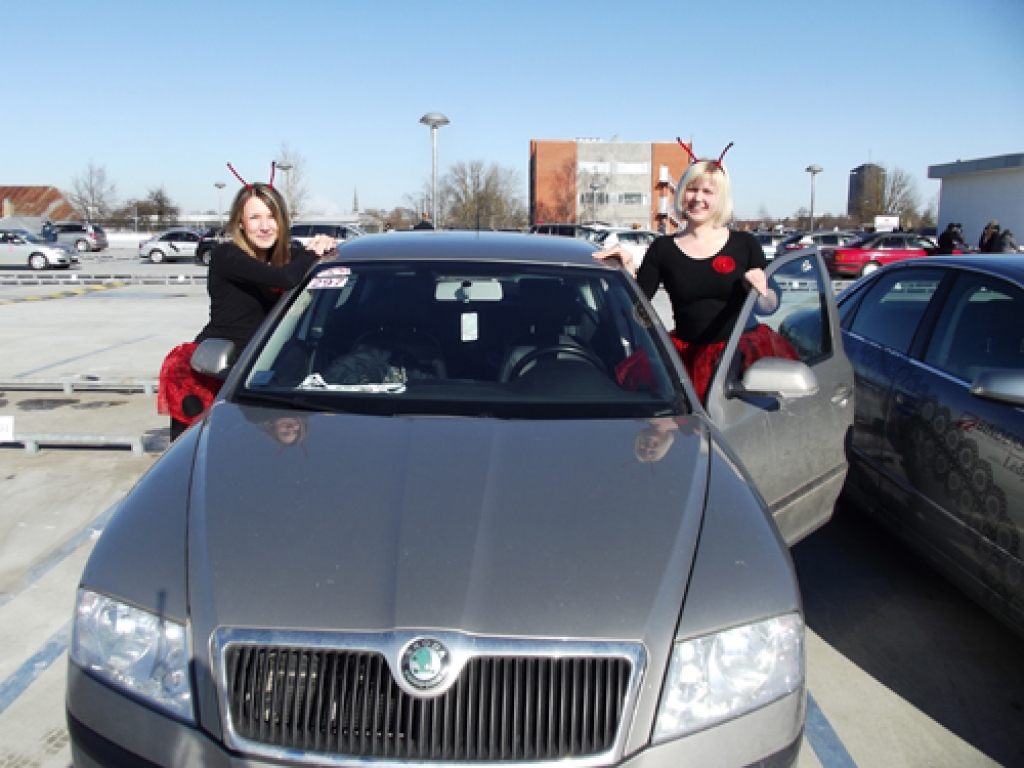 Sandra Serkova (no kreisās) un Diāna Upelniece pie rallija mašīnas Diānas darinātajos tērpos. 