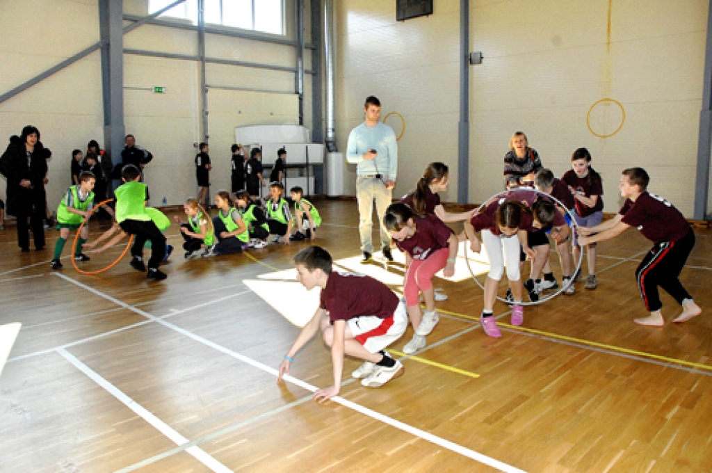 Uzvaras vidusskolas komanda mēģina pēc iespējas ātrāk veikt stafeti ar vingrošanas apli. 
