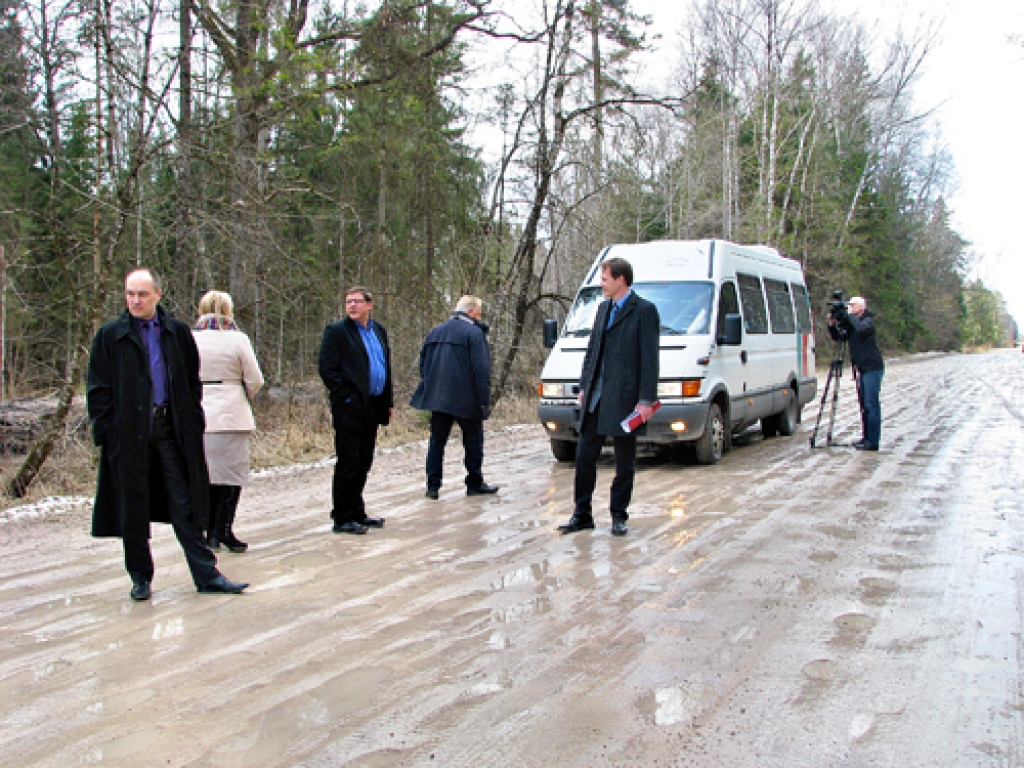 Saeimas deputāti iepazīst ar daudzām mazām bedrītēm «rotāto» ceļu no Ozolaines uz Skaistkalni.