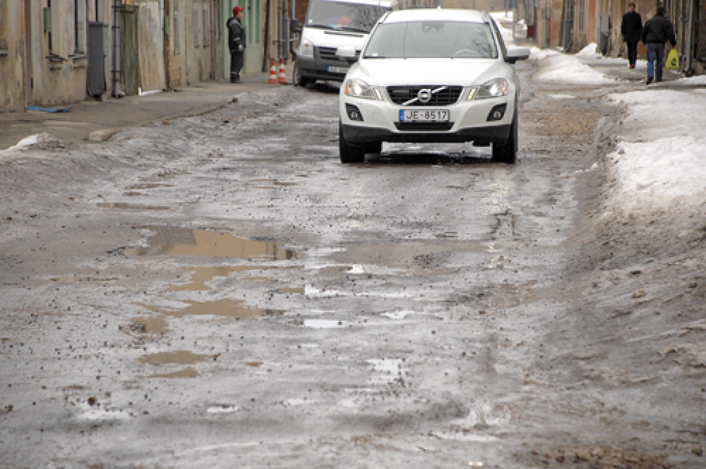 Rīgas ielā Bauskā pat apvidus auto šoferiem jāmeklē labākā braukšanas trajektorija. Dažos posmos izvairīties no bedrēm nav iespējams.