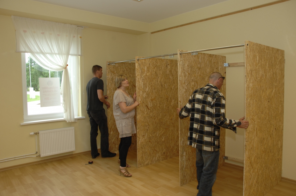 Rundāles novada Saulaines vēlēšanu iecirkņa priekšniece Maija Staņulāne vēro, kā strādnieki Jānis Rencis (no kreisās)  un Ints Bubinskis iekārto balsošanas kabīnes. 
Autors: Ivars Bogdanovs