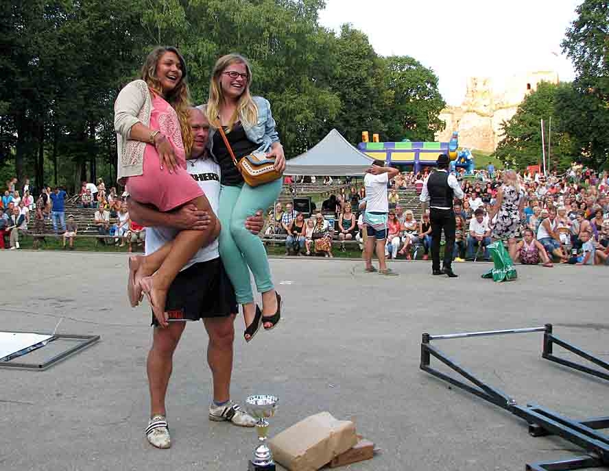 Sacensību uzvarētājs Dainis Zāģeris apliecina savu spēku, paceldams divas pielūdzējas. 
Autors: Vilnis Auzāns