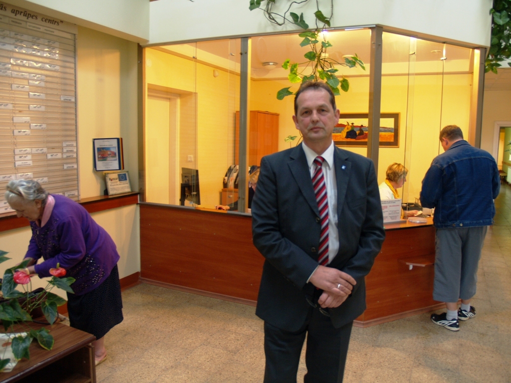 Sandris Kaidaks izvēlas bildēties pie reģistratūras, kur Veselības centrā redzama lielākā rosība.

