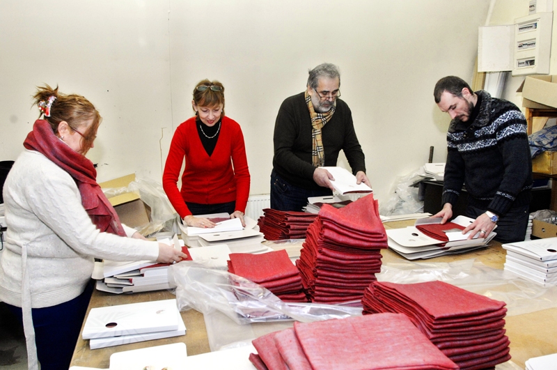 SIA «Geka» noliktavā steidz saiņot Latvijas prezidentūrai Eiropadomē sagatavotos suvenīrus – lina auduma šalles. Darbā iesaistījies uzņēmuma vadītājs Gūrijs Bulle (otrais no labās), kā arī Liene Lagzdiņa, Inese Ozola un Gaitis Putāns. 
Autors: Ivars Bogdanovs