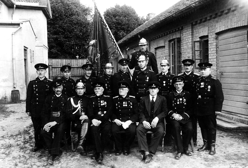 Bauskas Brīvprātīgo ugunsdzēsēju biedrības valdes un revīzijas komisijas locekļi ugunsdzēsēju depo pagalmā Pils ielā (tag. Plūdoņa iela 24). 
Autors: no Bauskas muzeja krājuma.
