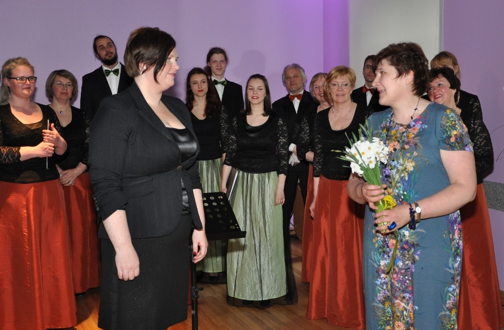 Līga Lauriņa, floristikas studijas vadītāja, ar dzejnieka narcisēm sveic diriģenti Sindiju Druvu (no kreisās).
Autors: Žanna Zālīte