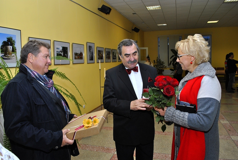 Jubilāru, izstādes autoru Nikolaju Ševirjovu (vidū) sveic uzņēmēji Aija un Ģirts Karpoviči.