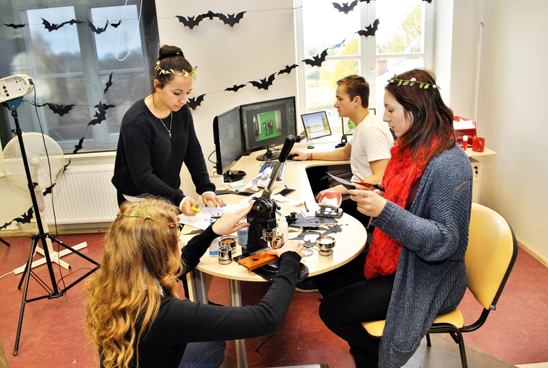 Linda Spundiņa (pirmā no labās) ar draugiem cītīgi gatavo dekorācijas Helovīna ballei, bet Andris Kāposts pie datora apstrādā bildes pēc kārtējās fotosesijas.